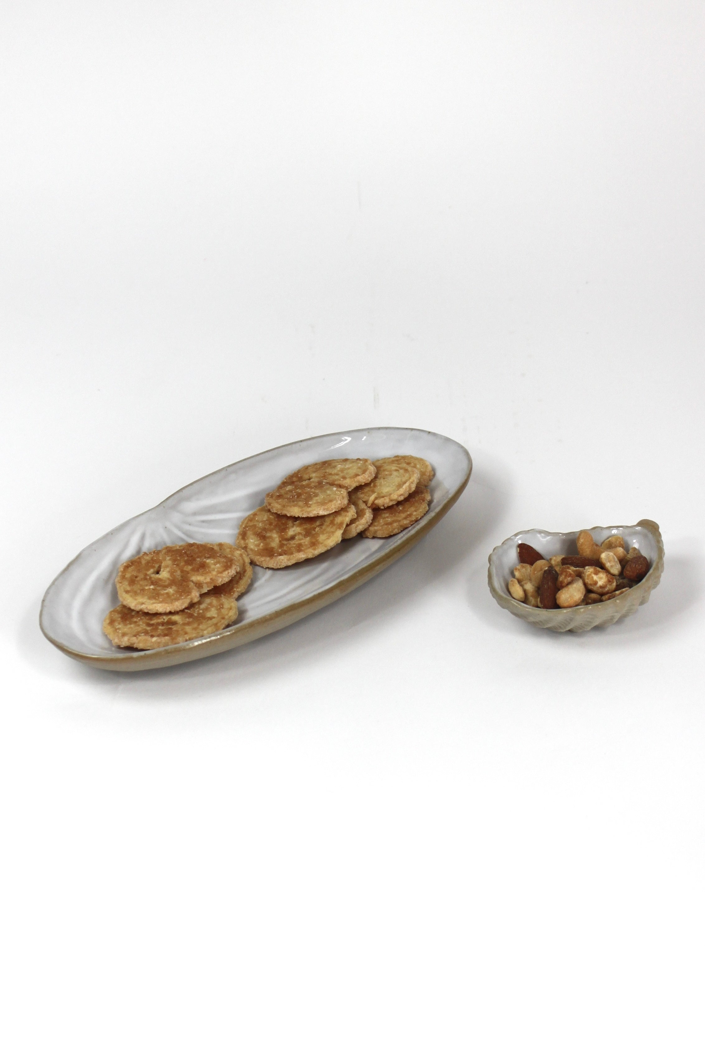 two shell shaped stoneware dishes - the larger in a clam shape, the smaller in an oyster shape