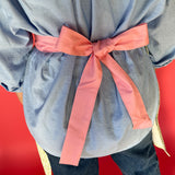 Person wearing a gray top with a pink bow against a red background