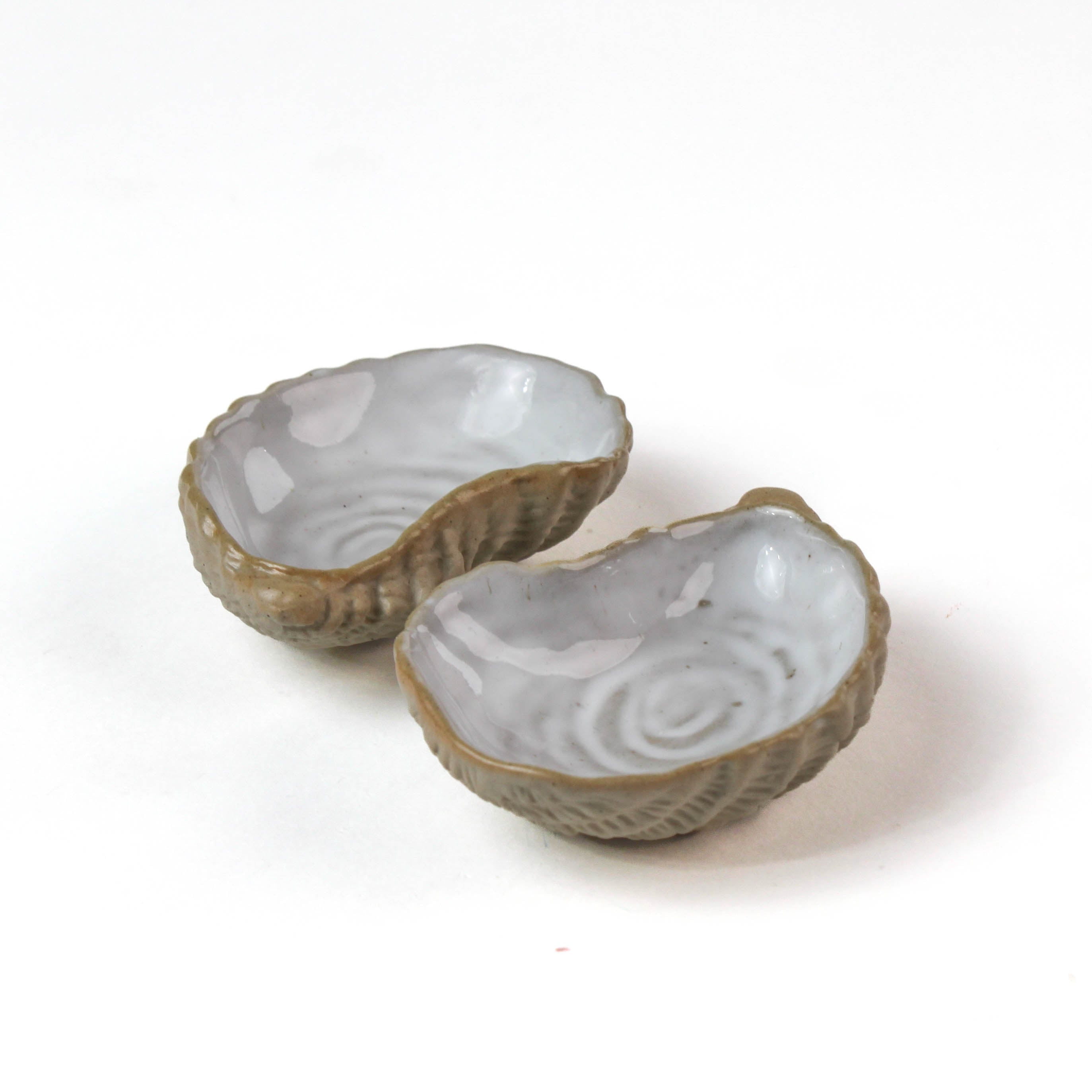 Two ceramic oyster shells with shellfish on a white background