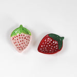 Two small strawberry-shaped ceramic bowls on a white background