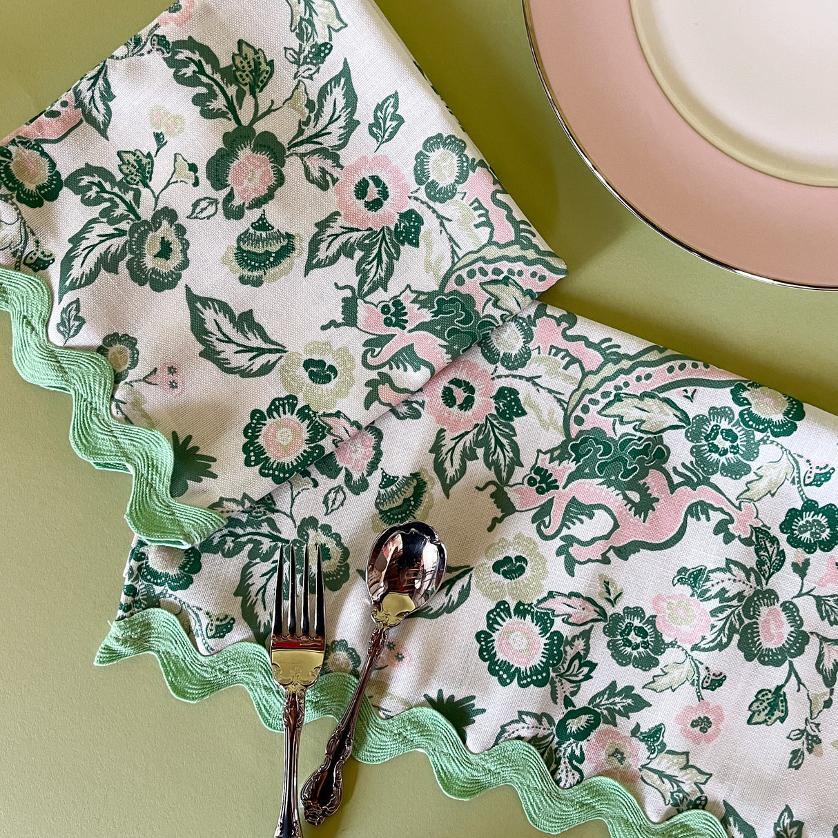 chinese dragon chinoiserie dinner napkins with pink china plate and silverware on a green background