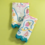 A pair of folded Bunnies and Bows print cloth dinner napkins in multicolor against a light green background.