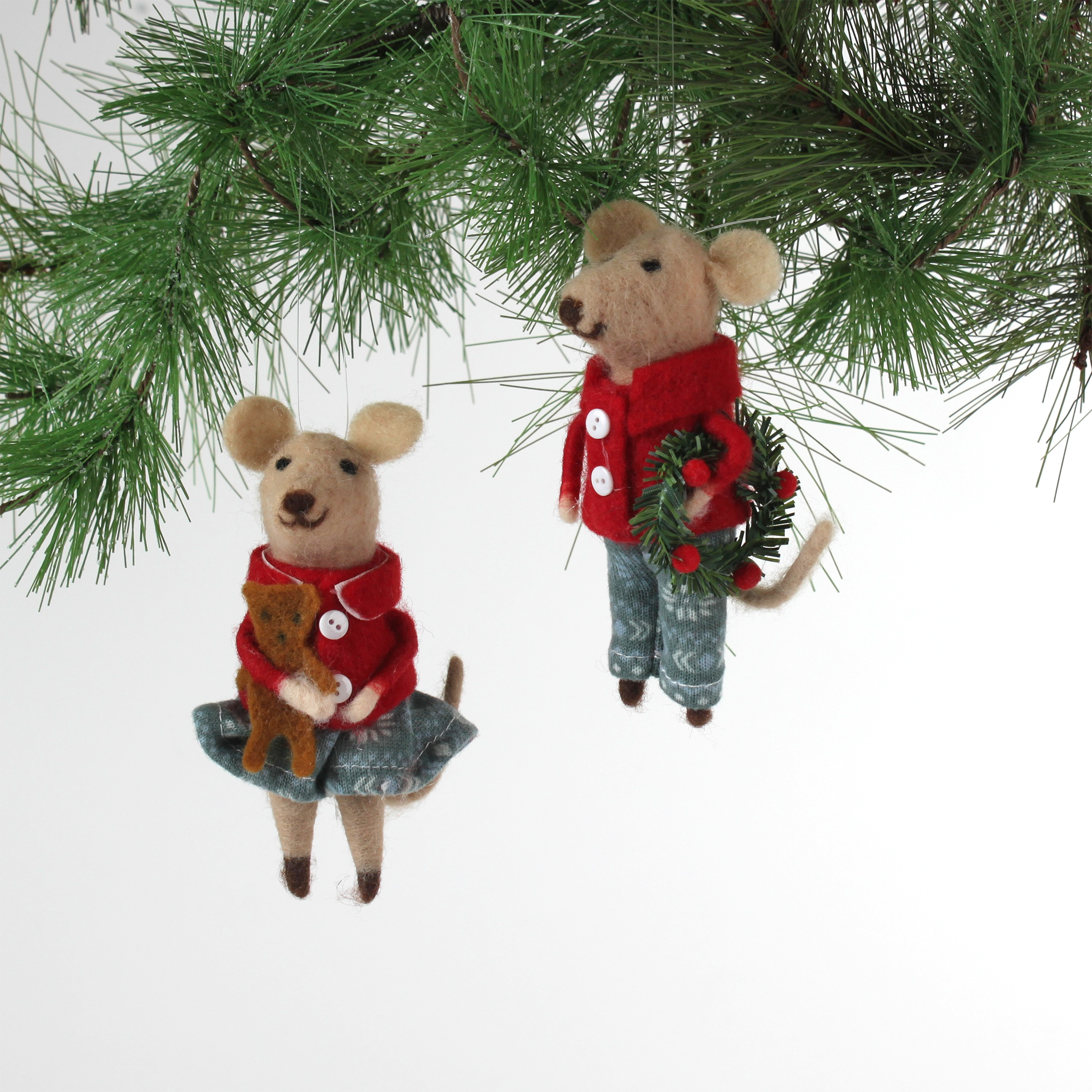 Two felt mouse ornaments wear festive red jackets and blue-green clothing—one holding a teddy bear and the other carrying a holiday wreath— and hanging from pine branches.