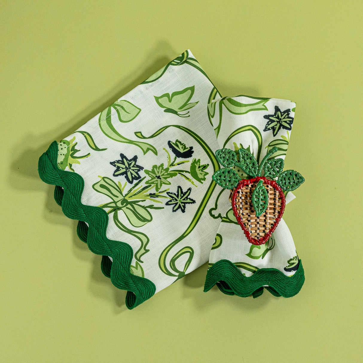 Bunnies and bow print fabric easter napkins in green with a strawberry napkin ring against a green background. 