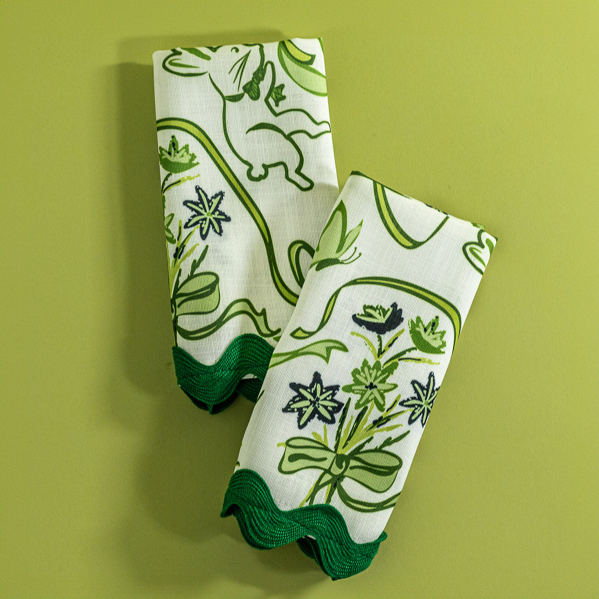 a pair of Bunnies and bow print fabric easter napkins in green against a green background. 