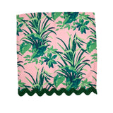 Palm leaf print napkin with lush green tropical foliage on a soft pink background and scalloped edge, stylish table linen perfect for Christmas tea towel styling, holiday entertaining, and seasonal home décor
