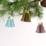 Set of pastel paper Christmas bell ornaments in blue, brown, and pink, featuring metallic gold bows and dotted details