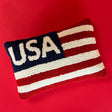 a patriotic USA pillow with red and white stripes and blue and white text that reads USA in the upper left corner