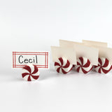 Red and white peppermint candy christmas place card holders with a name tag labeled 'Cecil' on a white background