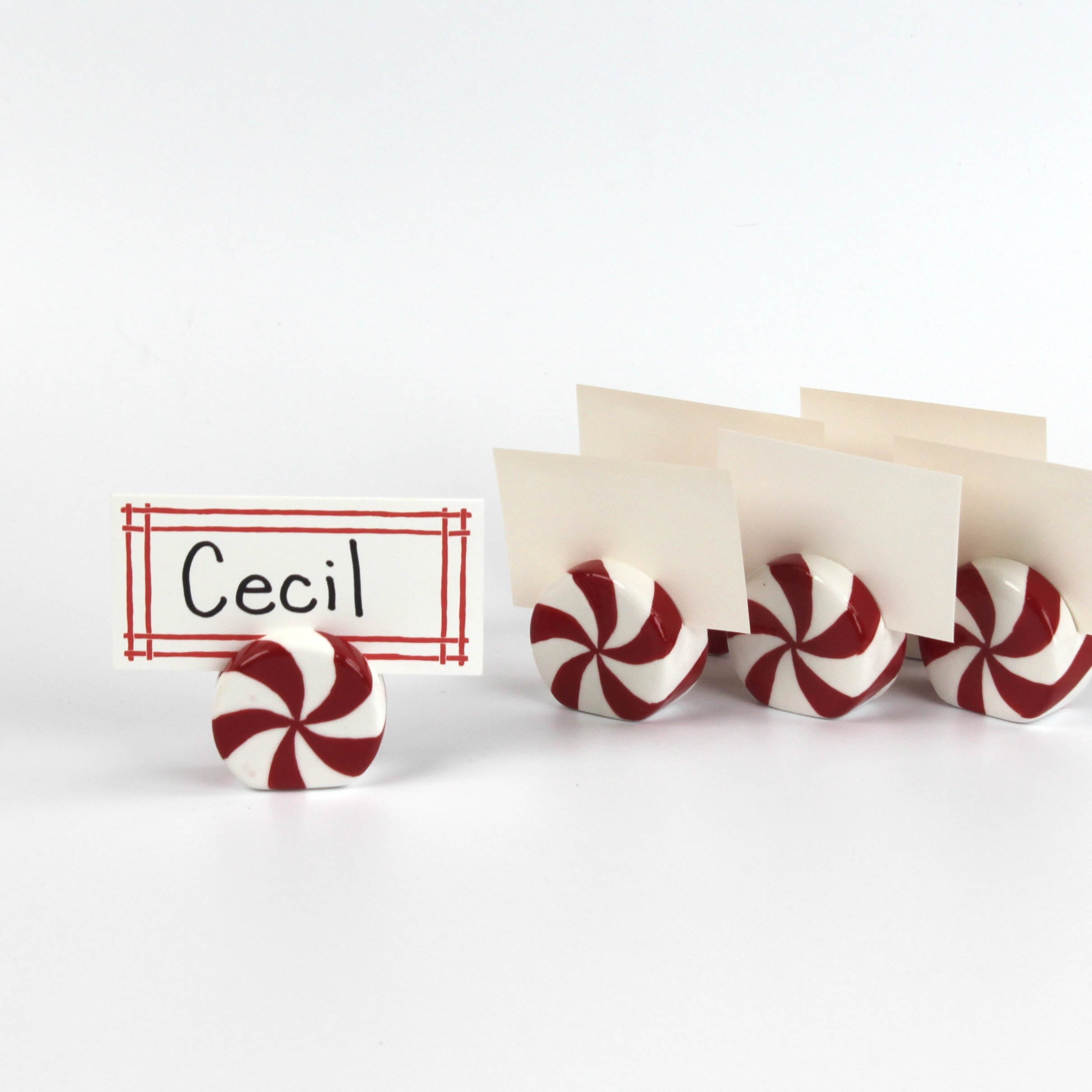 Red and white peppermint candy christmas place card holders with a name tag labeled 'Cecil' on a white background