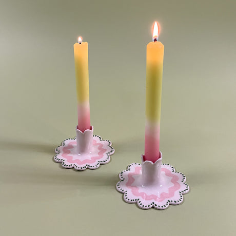A pair pastel taper candles in Scalloped ceramic candle holders with a pink and green wavy motif