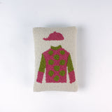 Rectangular decorative pillow with a design of a jockey outfit in pink and green, featuring polka dots on the shirt and a matching pink riding cap on a cream background.