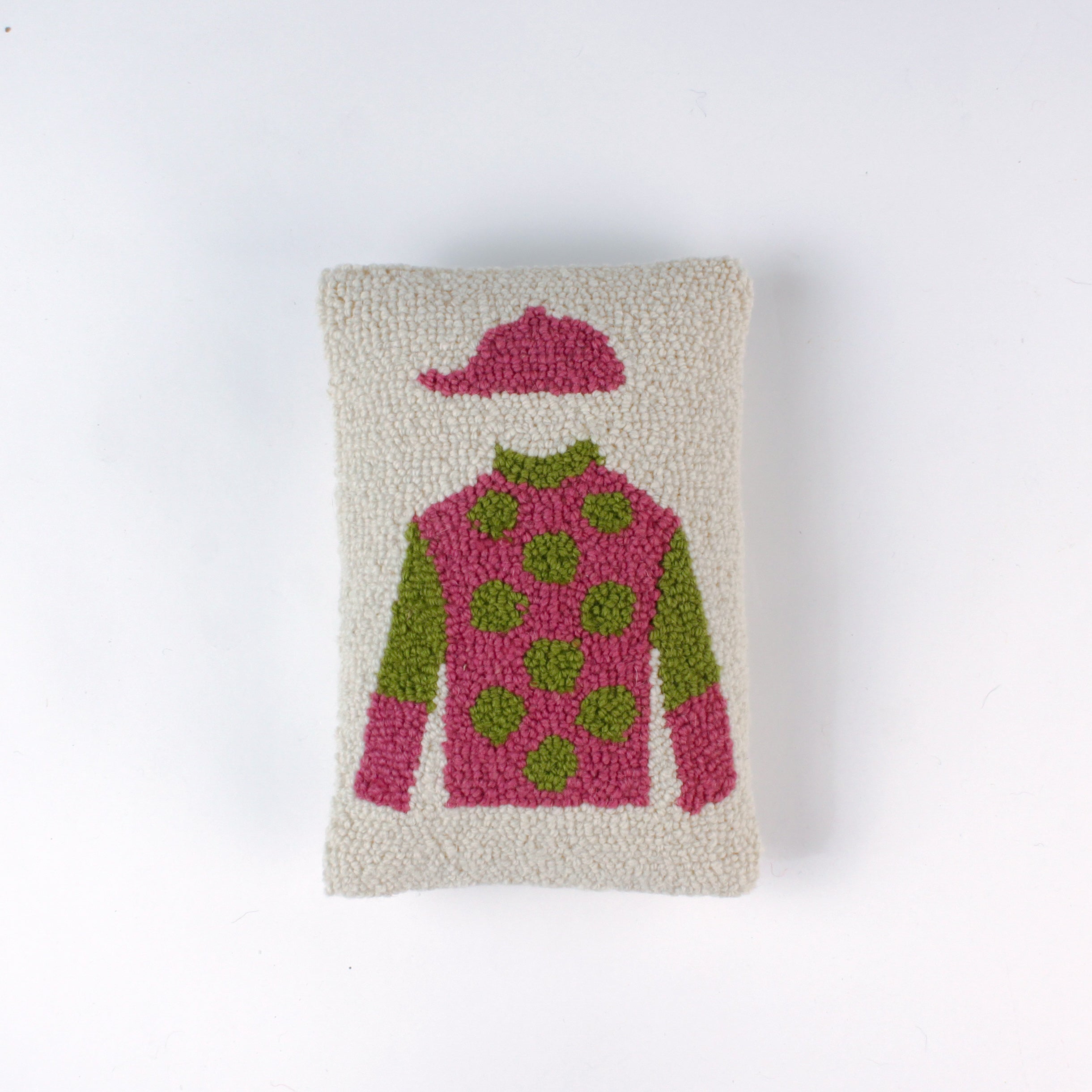 Rectangular decorative pillow with a design of a jockey outfit in pink and green, featuring polka dots on the shirt and a matching pink riding cap on a cream background.