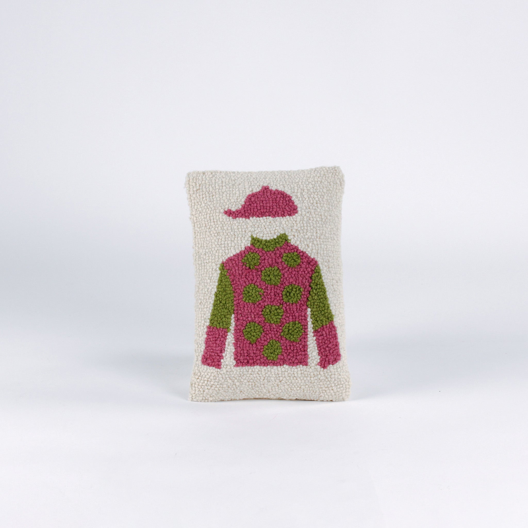 Rectangular decorative pillow with a design of a jockey outfit in pink and green, featuring polka dots on the shirt and a matching pink riding cap on a cream background.