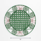 Round pink and green rattan placemat with pink woven accents and spiral details, 15 inch diameter