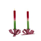 set of pink bow shaped candle holders with green and red canles and a glossy finish on white background