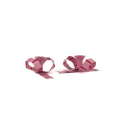 set of pink bow shaped candle holders with glossy finish on white background