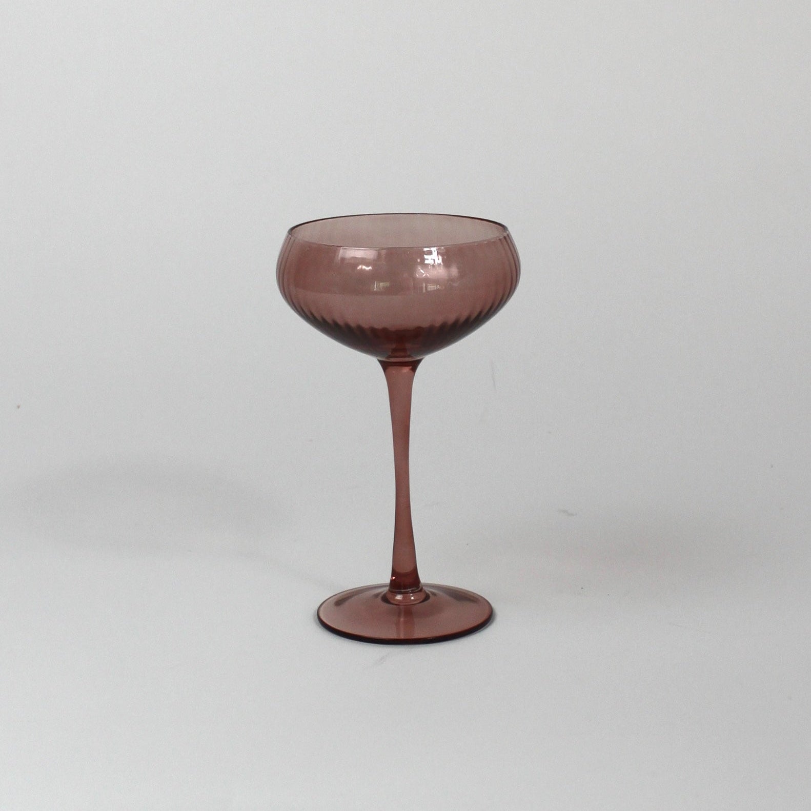 a pink coupe glass on a white background