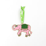 Pink elephant ornament with green saddle on a white background
