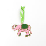 Pink elephant ornament with green saddle on a white background