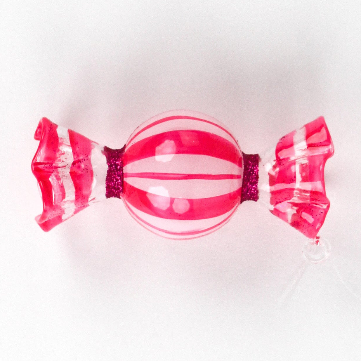 a pink glass candy christmas ornament on a white background