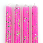 Pink glitter taper candles with green and gold confetti-style sparkle detailing for festive table decor.