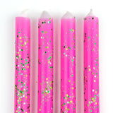Pink glitter taper candles with green and gold confetti-style sparkle detailing for festive table decor.