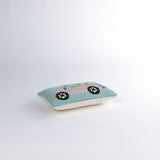 side of a Rectangular decorative pillow with a design of a pink golf cart featuring green seats, a blue golf bag, and a pink-and-white canopy on a light blue background.