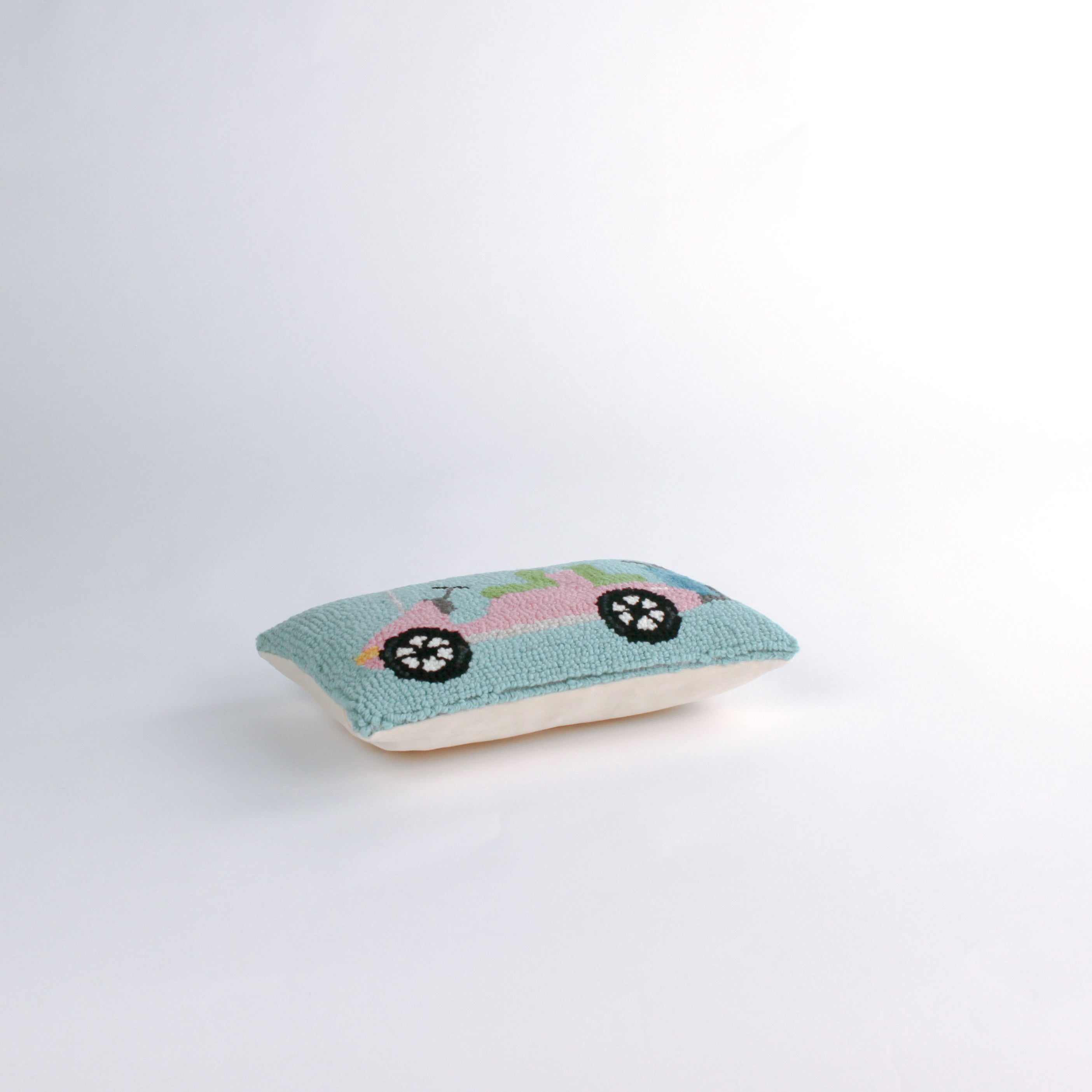 side of a Rectangular decorative pillow with a design of a pink golf cart featuring green seats, a blue golf bag, and a pink-and-white canopy on a light blue background.