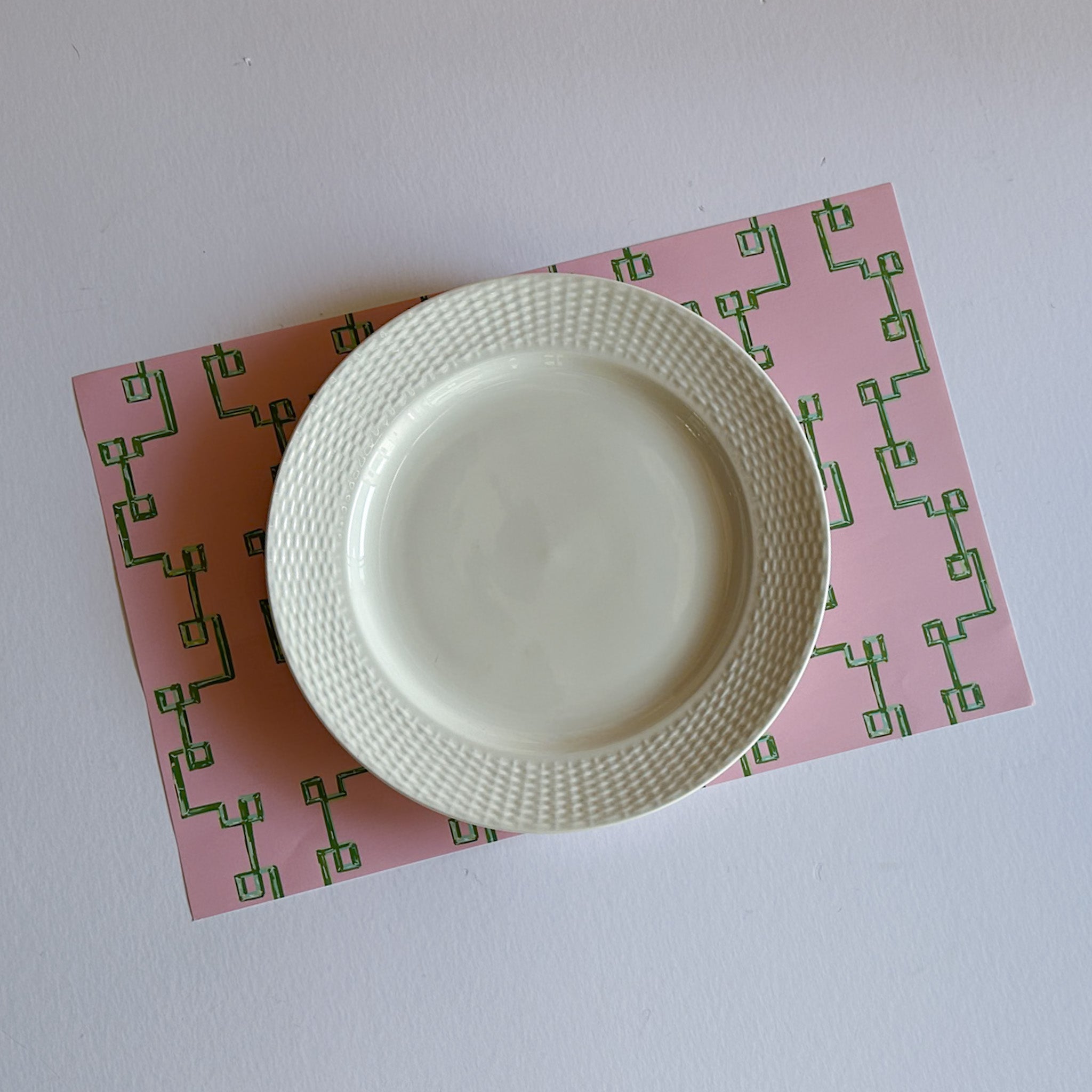 pink bamboo lattice paper placemat with white plate top view table setting