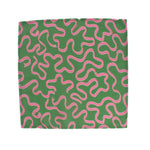 Green napkin with playful pink squiggle pattern on a white background, modern table linen perfect for Christmas tea towel styling, holiday entertaining, and seasonal home décor