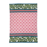 A pink and green chinoiserie tea towel featuring a central pink lattice pattern and green floral border against a white background. 