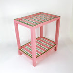 A pink side table with a green and white striped pattern named "Harbor Trail" by madcap cottage