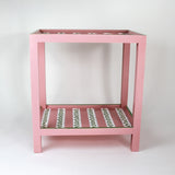 A pink side table with a green and white striped pattern named "Harbor Trail" by madcap cottage