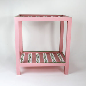 A pink side table with a green and white striped pattern named "Harbor Trail" by madcap cottage