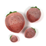 a set of four pink ceramic strawberry dishes in graduating sizes.