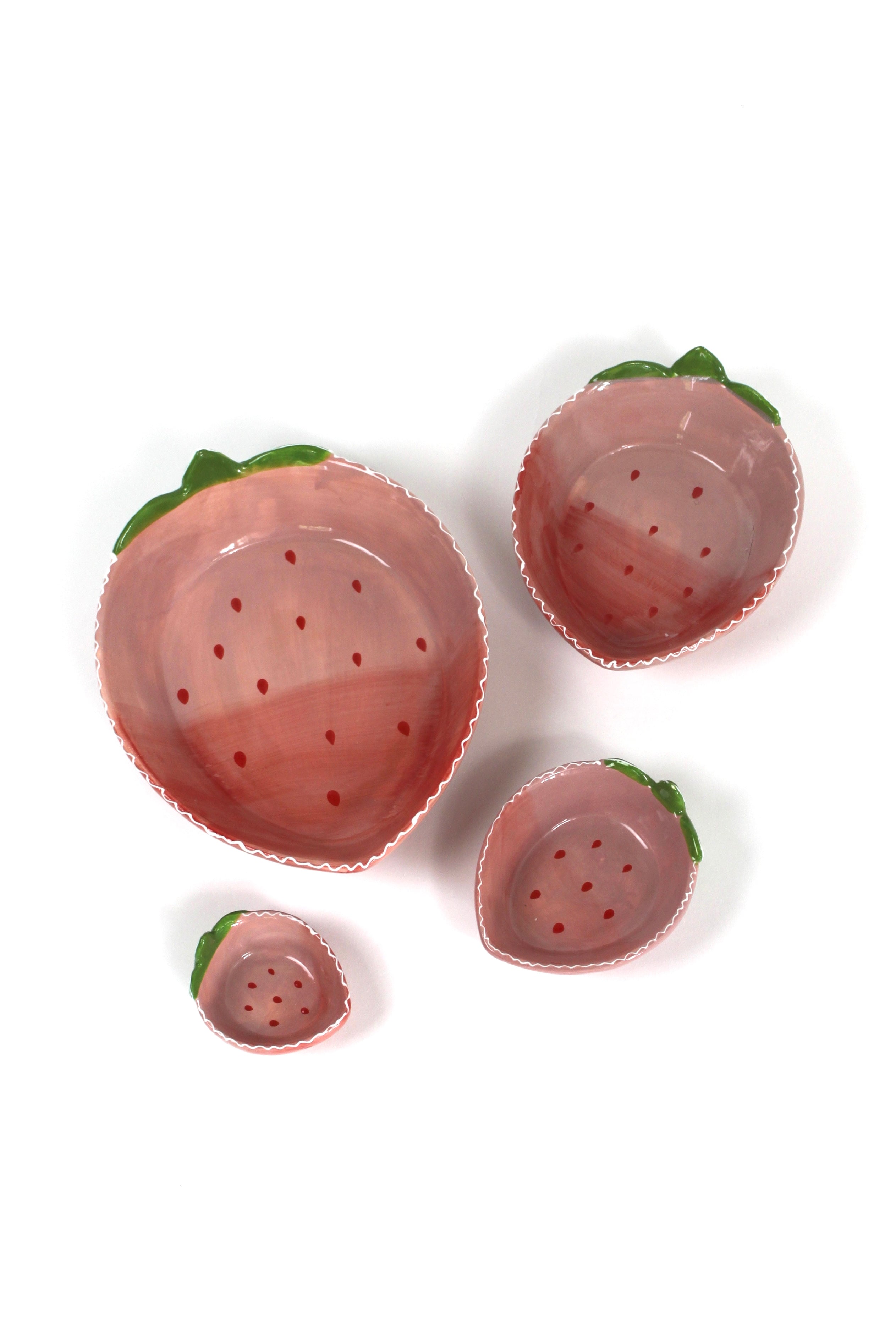 a set of four pink ceramic strawberry dishes in graduating sizes.