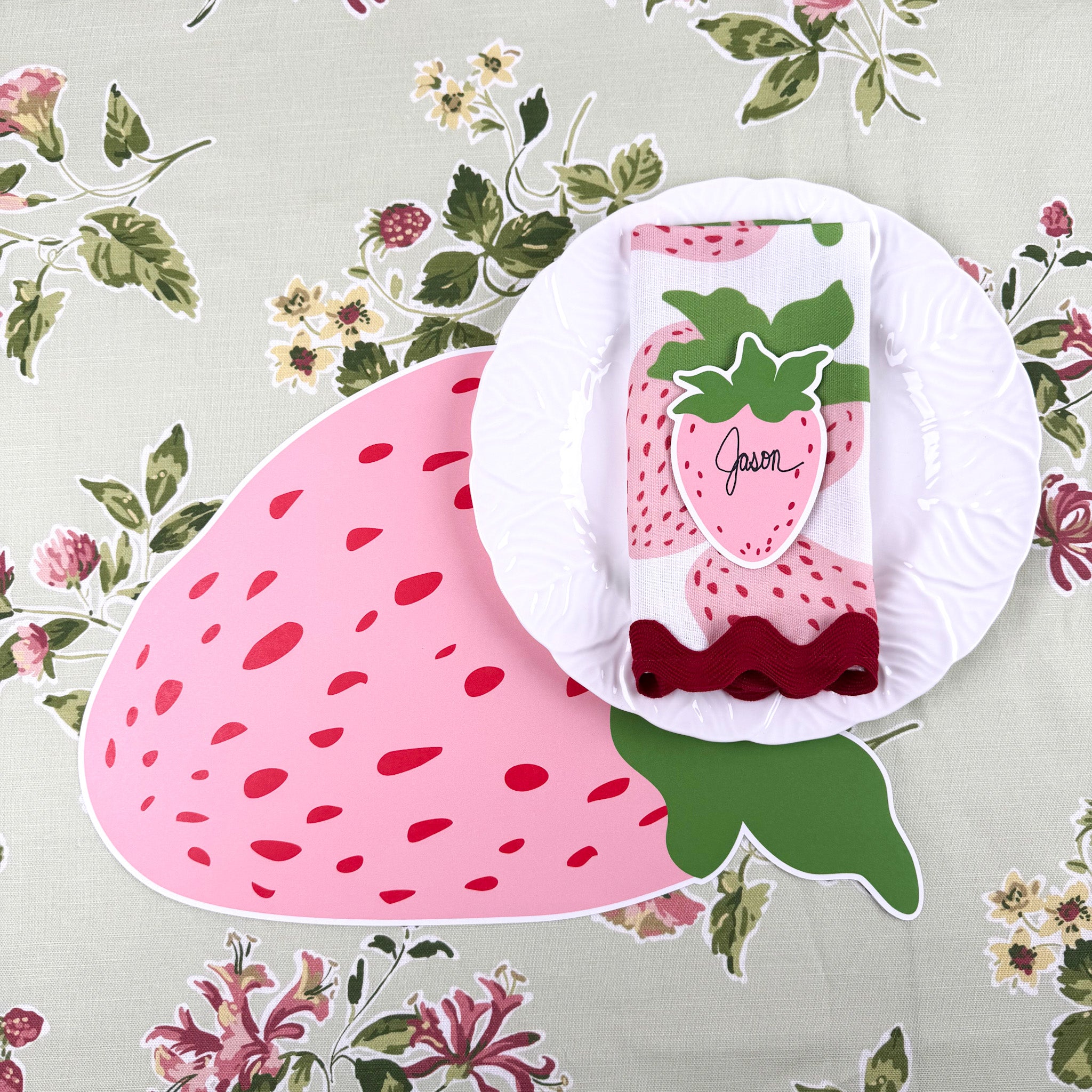 strawberry die-cut paper placemat spring table setting with white plate and strawberry napkin.
