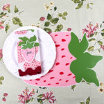strawberry die-cut paper placemat spring table setting with white plate, strawberry napkin, and floral tablecloth.