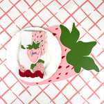 strawberry die-cut paper placemat spring table setting with white plate, strawberry napkin, and patterned tablecloth.
