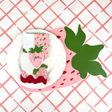 strawberry die-cut paper placemat spring table setting with white plate, strawberry napkin, and patterned tablecloth.
