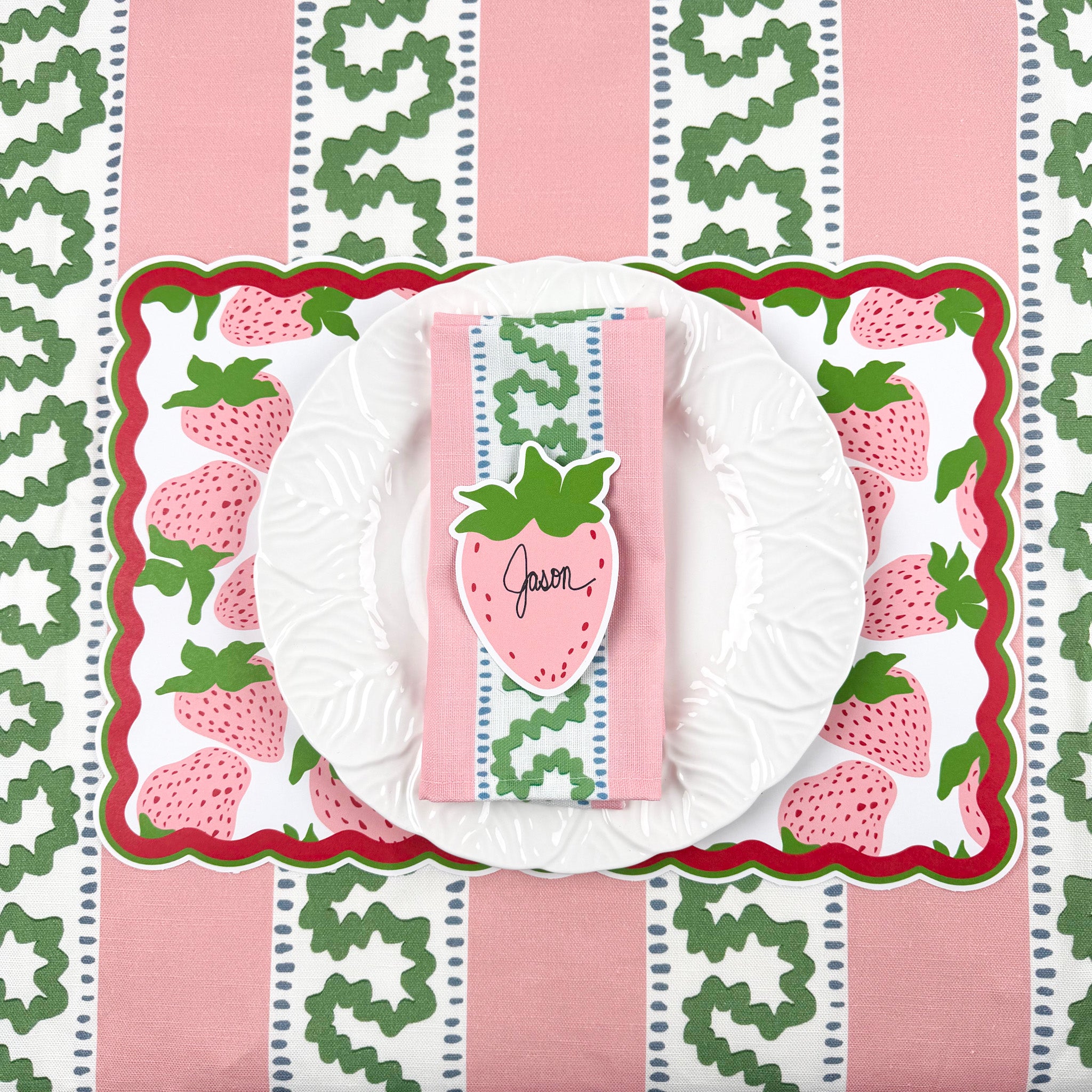 strawberry paper placemat spring table setting with white plate, striped napkin, and strawberry place card.