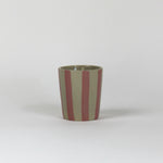 A pink striped ceramic cup in on a white background. 