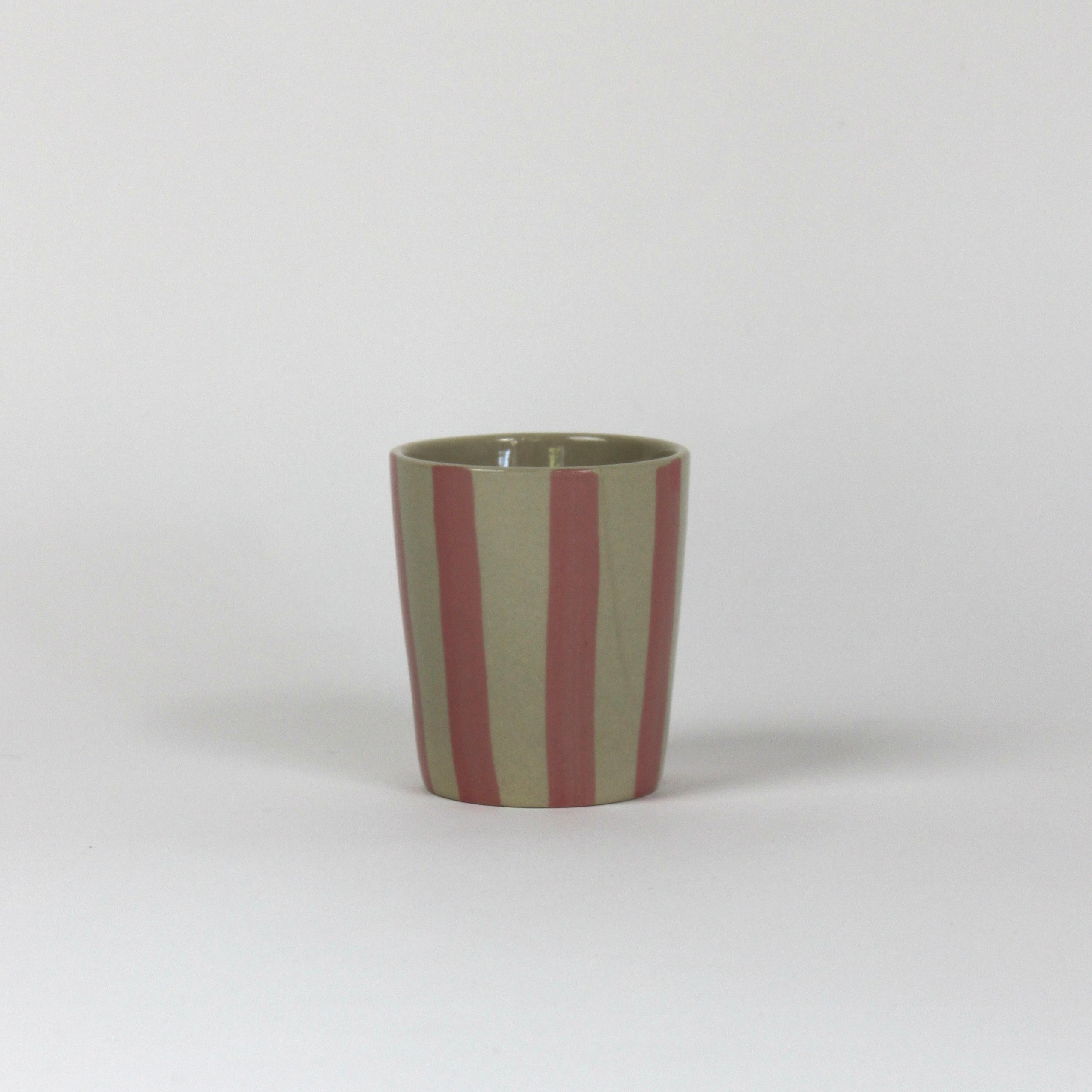 A pink striped ceramic cup in on a white background. 