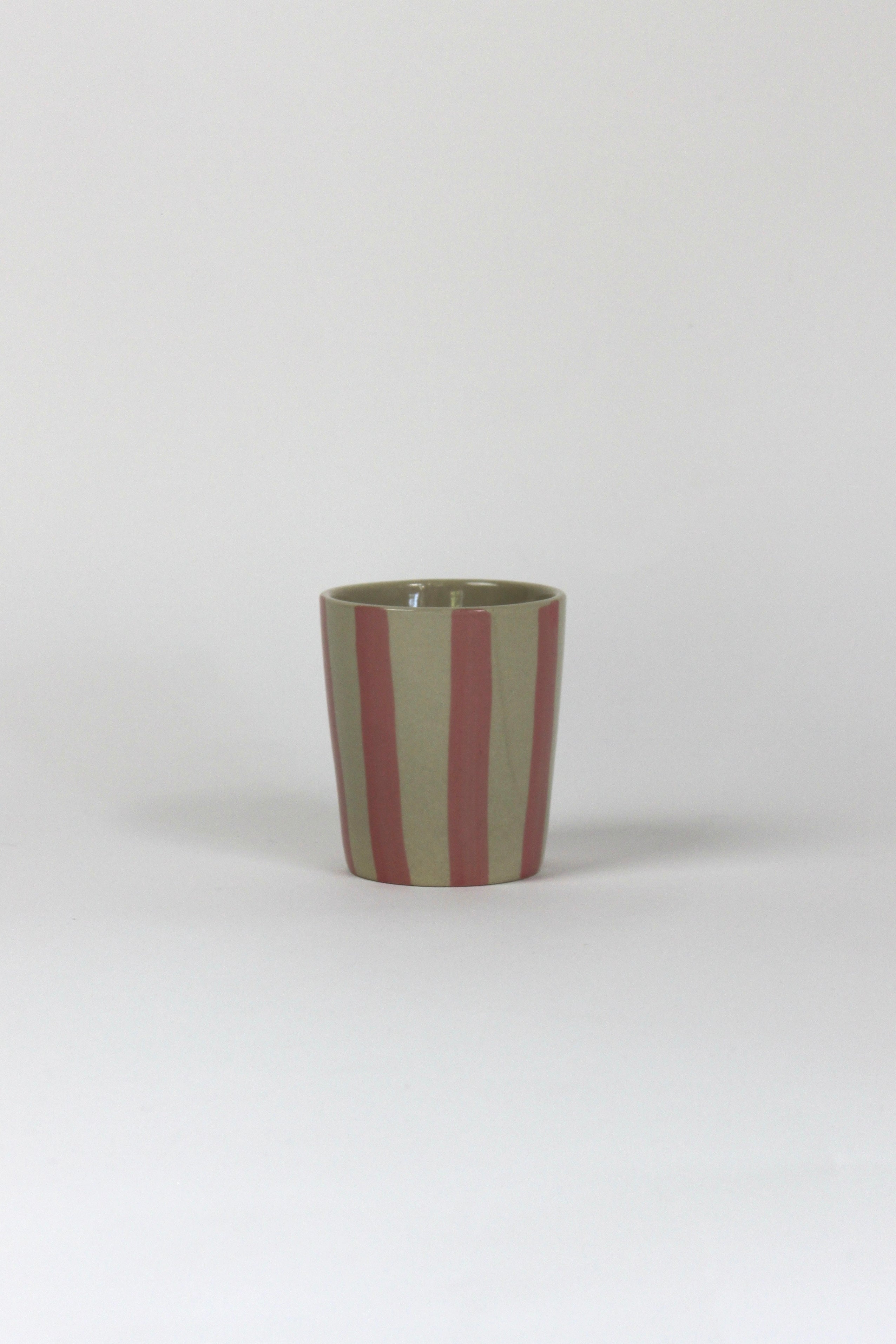 A pink striped ceramic cup in on a white background. 