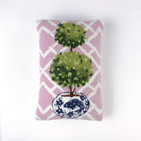 Rectangular decorative pillow with a pink and white lattice background featuring a green double topiary plant in a blue and white chinoiserie-style pot.