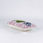 side of a Rectangular decorative pillow with a pink and white lattice background featuring a green double topiary plant in a blue and white chinoiserie-style pot.
