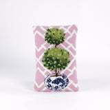Rectangular decorative pillow with a pink and white lattice background featuring a green double topiary plant in a blue and white chinoiserie-style pot.