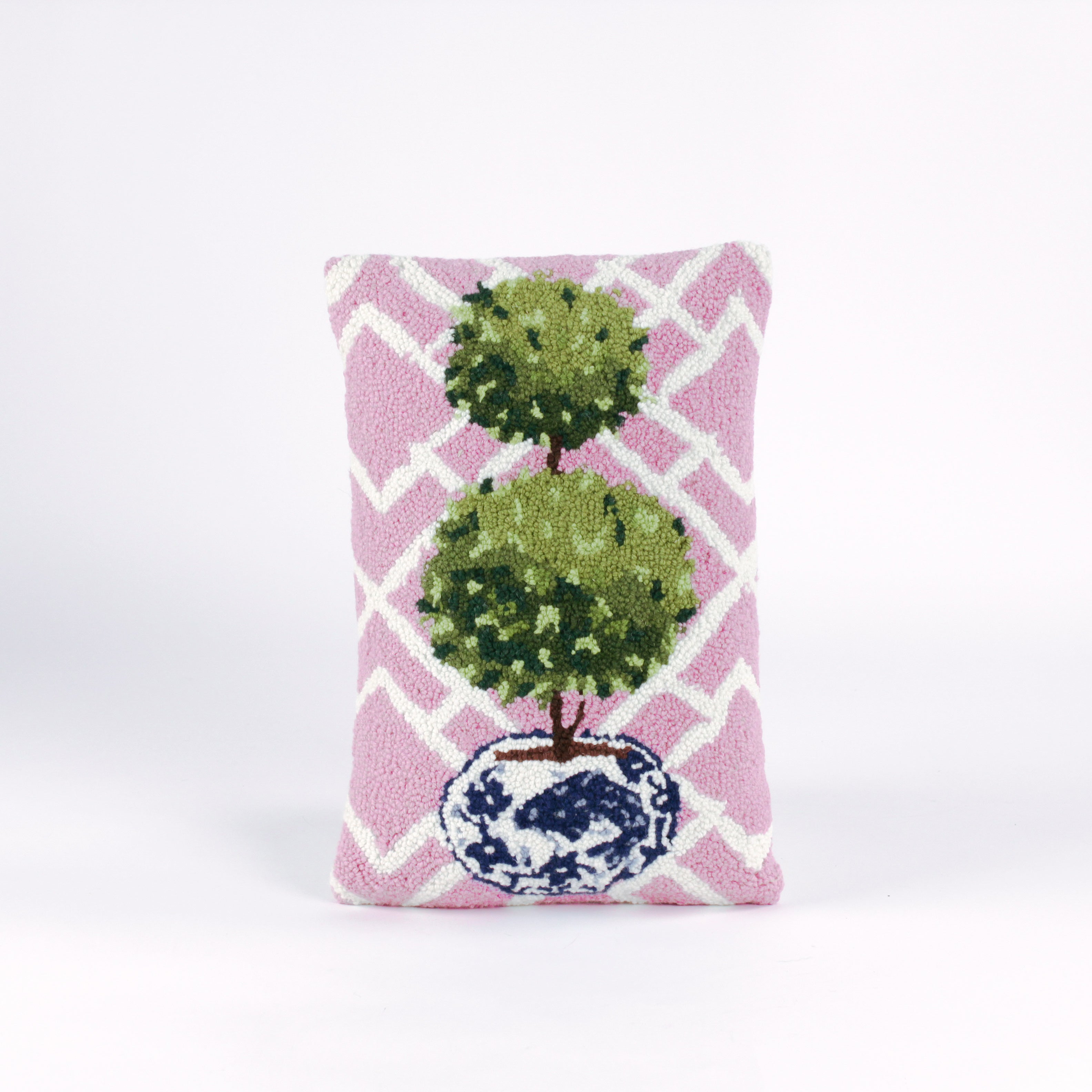 Rectangular decorative pillow with a pink and white lattice background featuring a green double topiary plant in a blue and white chinoiserie-style pot.