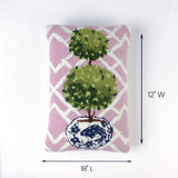 Pink rectangular pillow with a double topiary design in a blue and white pot shown with 18 inch length and 12 inch width.